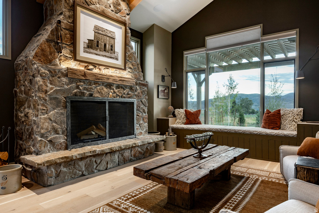 Expansive stone fireplace with a rustic wood mantel and metal-framed screen
