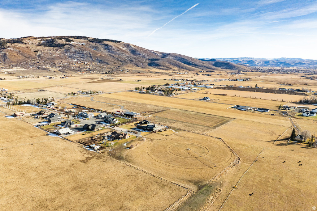 Expansive rural landscape featuring a cluster of residential properties, agricultural fields, and distant mountain ranges