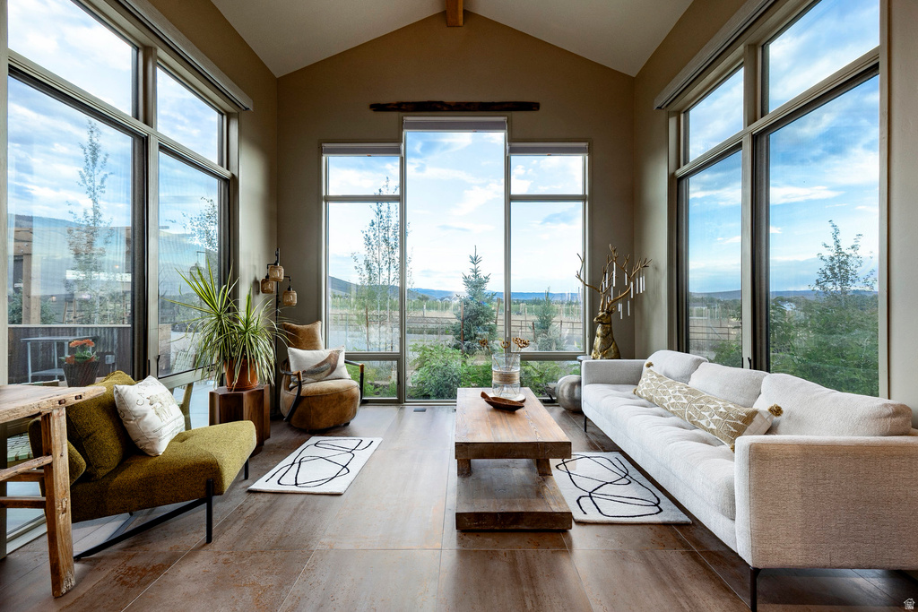 Vaulted ceiling great room featuring expansive floor-to-ceiling windows, wood-finish flooring, and a substantial wood coffee table