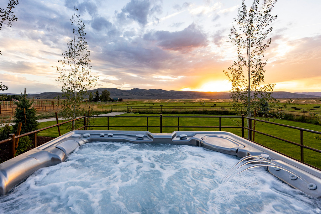 Outdoor spa featuring bubbling water and a water feature, set against a backdrop of mountains and open fields