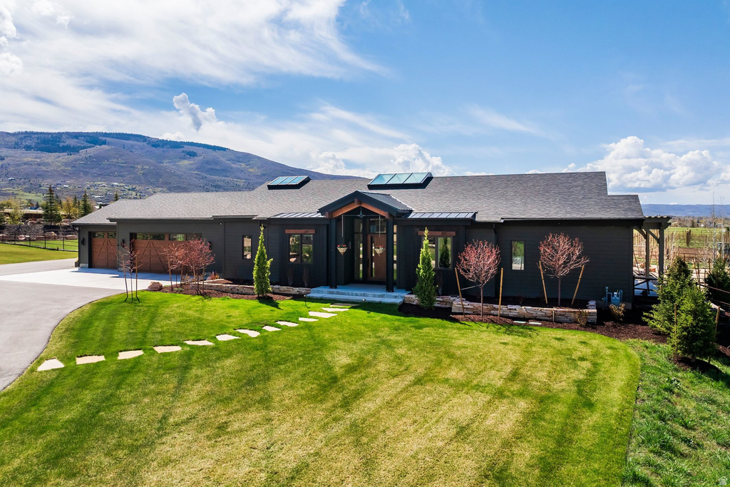Contemporary residence featuring dark siding, a dark shingle roof, and multiple skylights