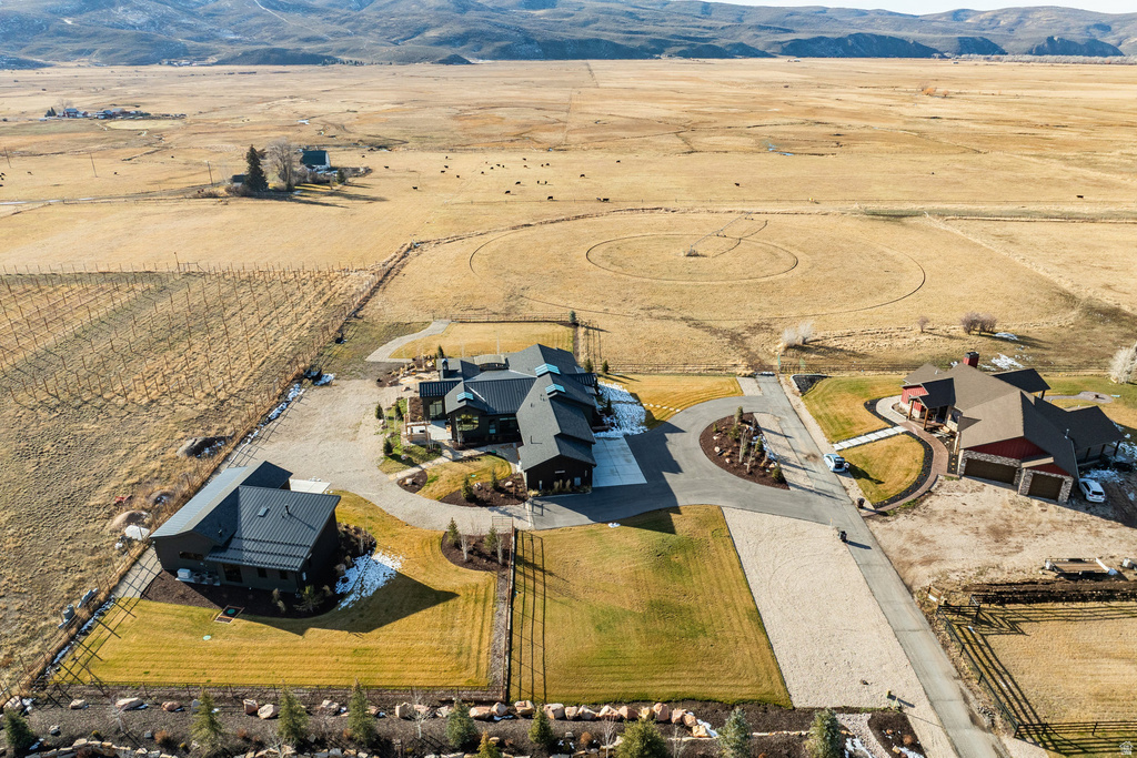 Expansive property featuring multiple structures, a circular driveway, and broad open land stretching to distant mountains
