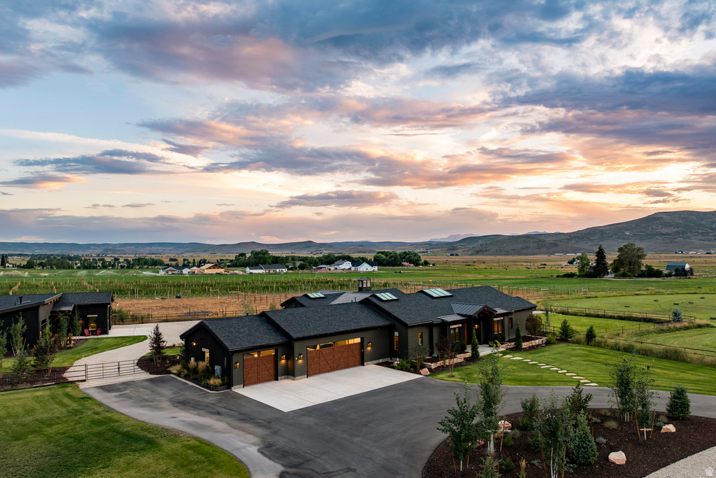 Expansive single-story residence featuring a dark exterior with natural wood-finish garage doors