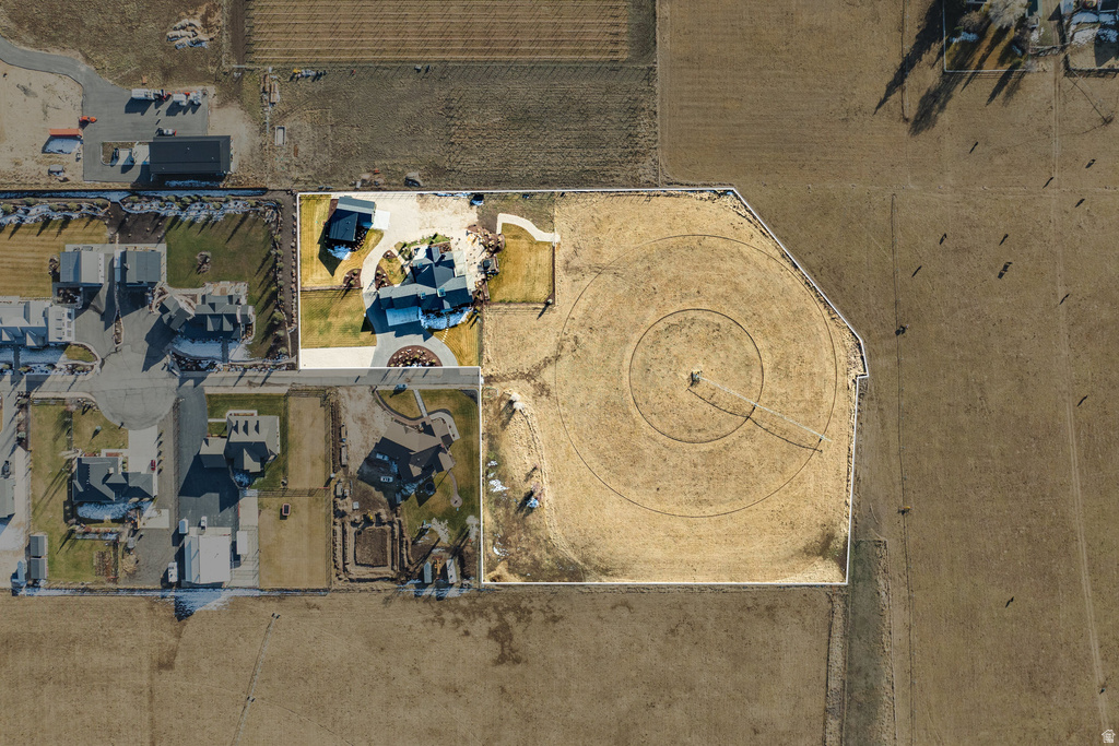 Expansive property featuring a circular driveway, multiple structures, a large cultivated field with irrigation, and a substantial land area