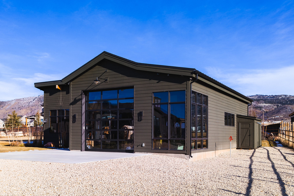 Contemporary dark-toned exterior featuring extensive window elements and a large glass-paneled garage door