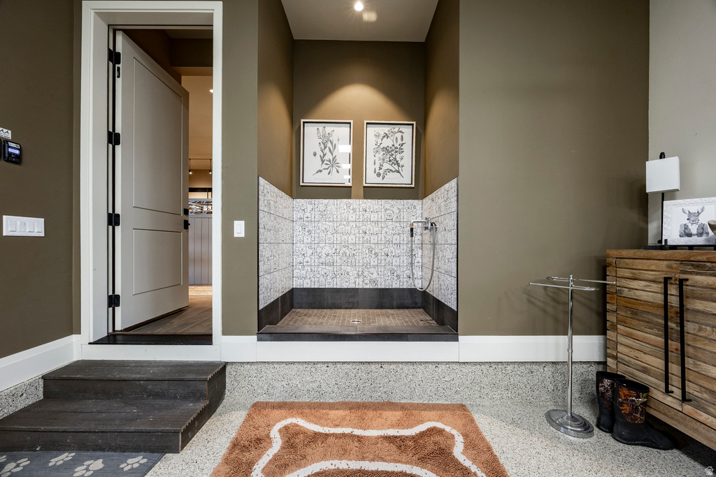 Dedicated pet wash station featuring tiled walls, a built-in shower, and a slatted base