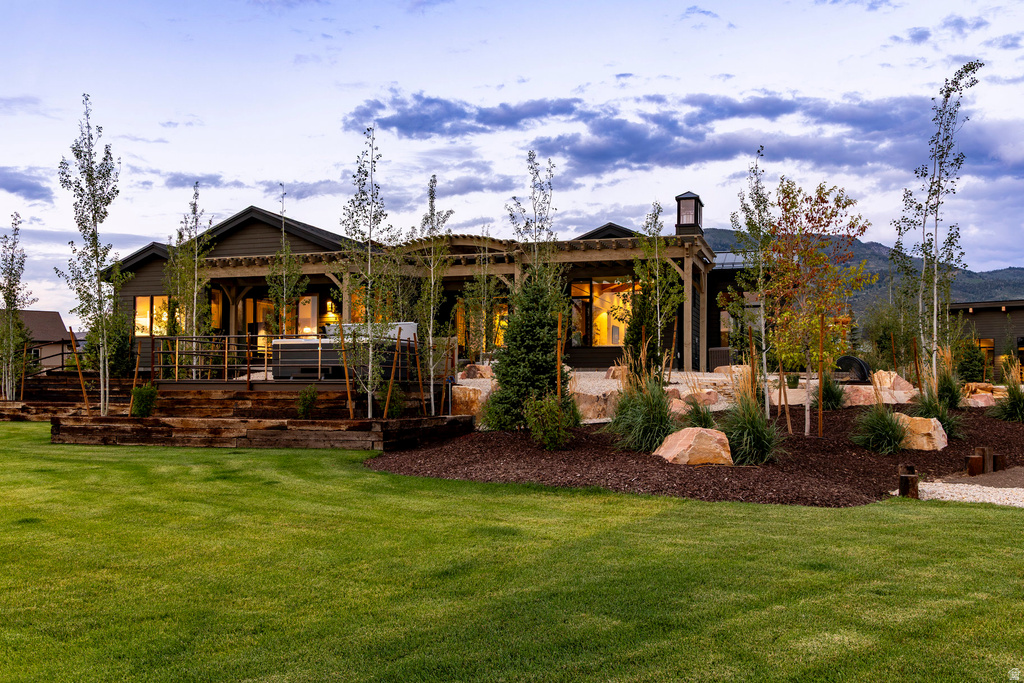 Expansive backyard featuring a manicured lawn, tiered landscaping with natural rock elements, and mature trees