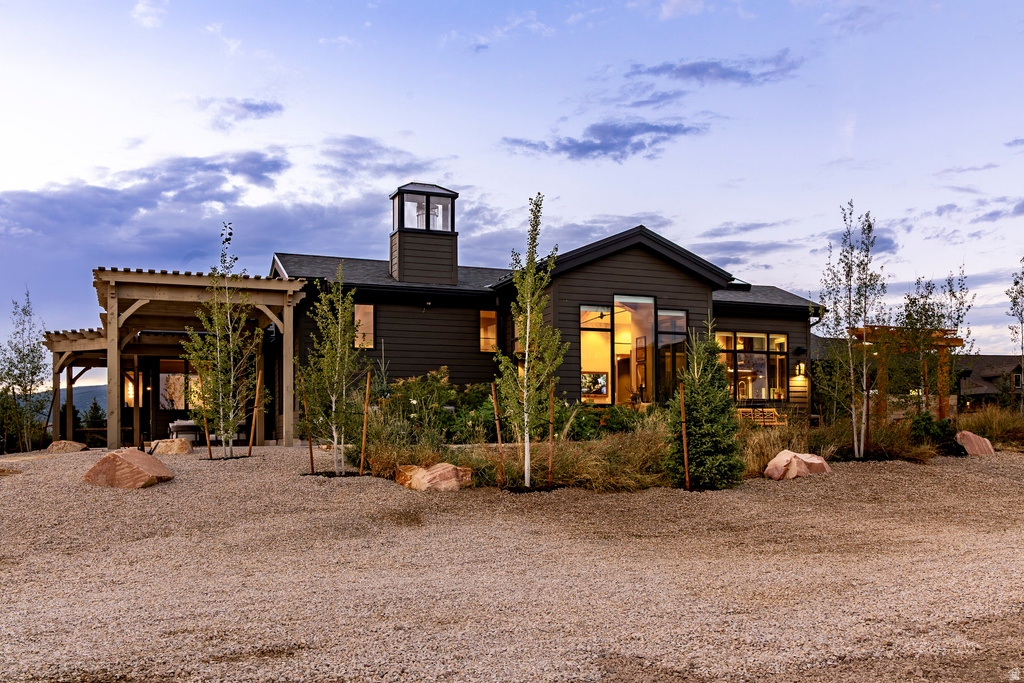 Contemporary exterior with dark siding, a prominent cupola, and a pergola-covered patio