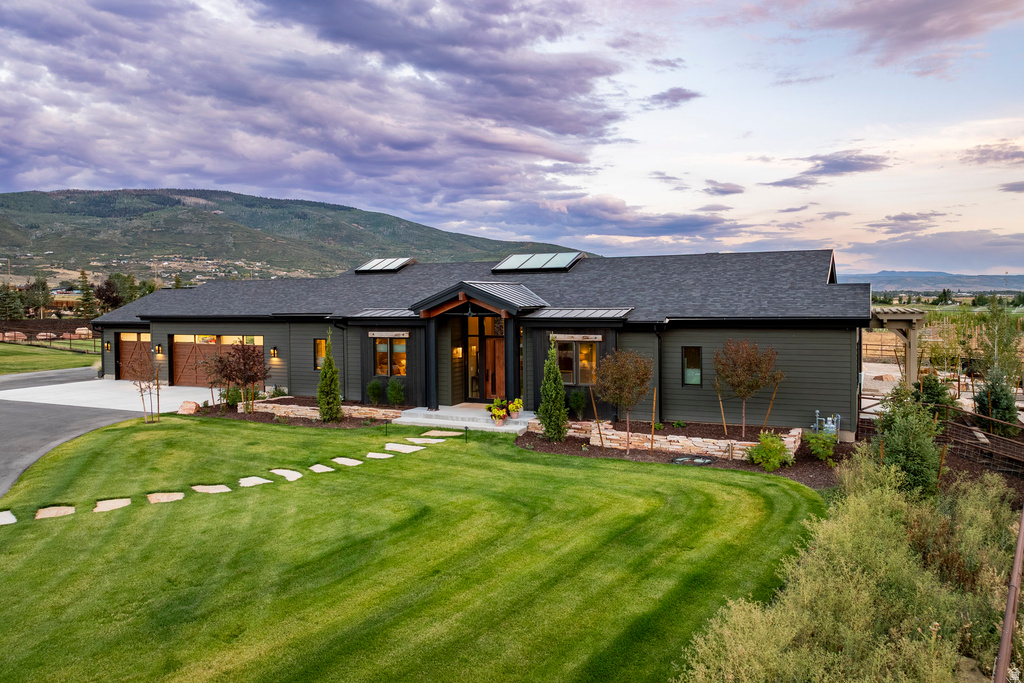 Contemporary ranch-style residence featuring dark gray siding, a dark shingle roof, and multiple skylights