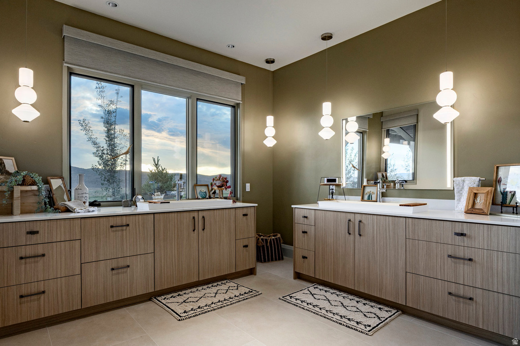 Expansive vanity area featuring dual wood-finish cabinetry with multiple drawers, white countertops, and modern pendant lighting fixtures