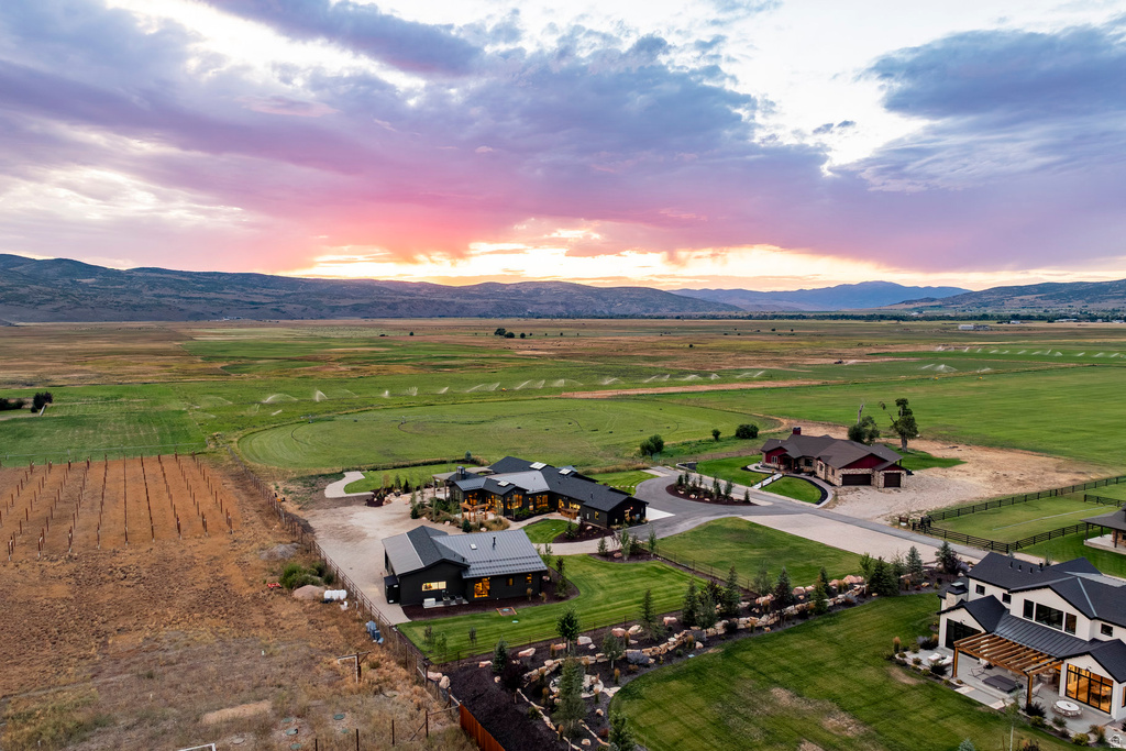 Expansive property featuring multiple contemporary residences, manicured lawns, paved driveways, and distant mountain ranges