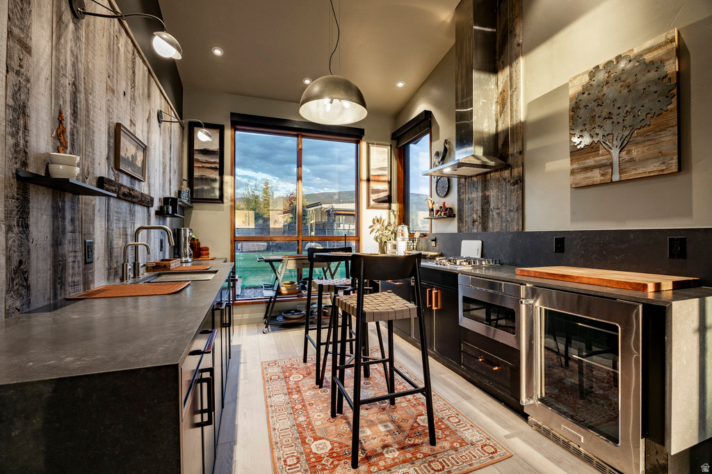 Modern kitchen featuring wood-finish flooring, concrete-finish countertops, and a wood plank accent wall