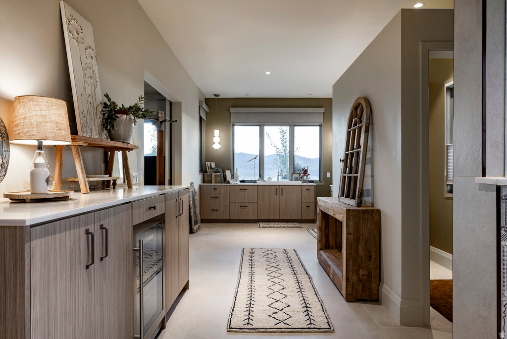 Hallway with built-in cabinetry, integrated beverage refrigerator, light-toned flooring, recessed lighting, and a window with mountain scenery