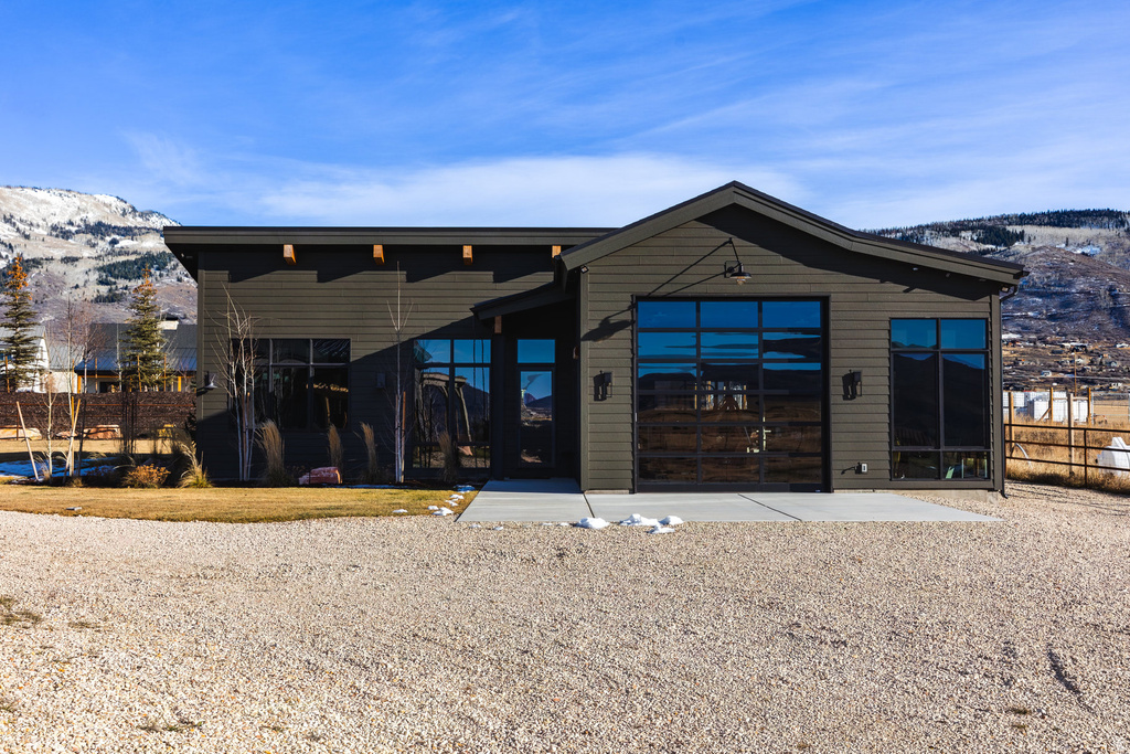 Modern exterior featuring dark siding, extensive fenestration, and a large glass-paned garage door