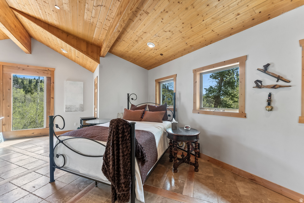 Vaulted wood-plank ceiling with exposed beams, recessed lighting, wood-trimmed windows, and tile flooring
