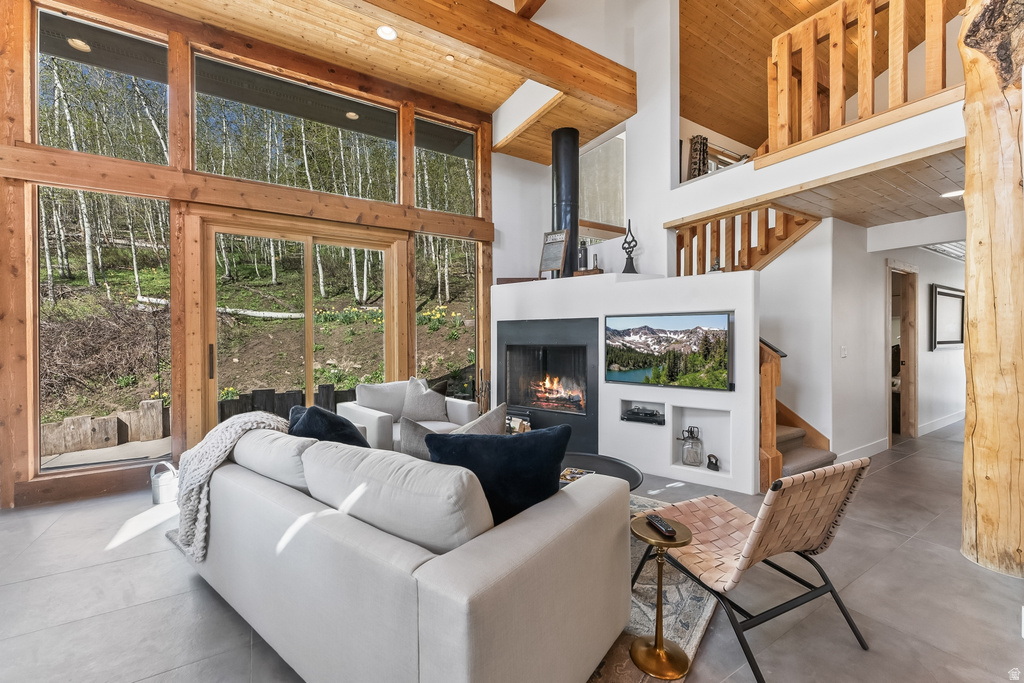 Great room featuring a vaulted ceiling with exposed wood beams, a floor-to-ceiling fireplace with built-in shelving, and large windows with sliding glass doors