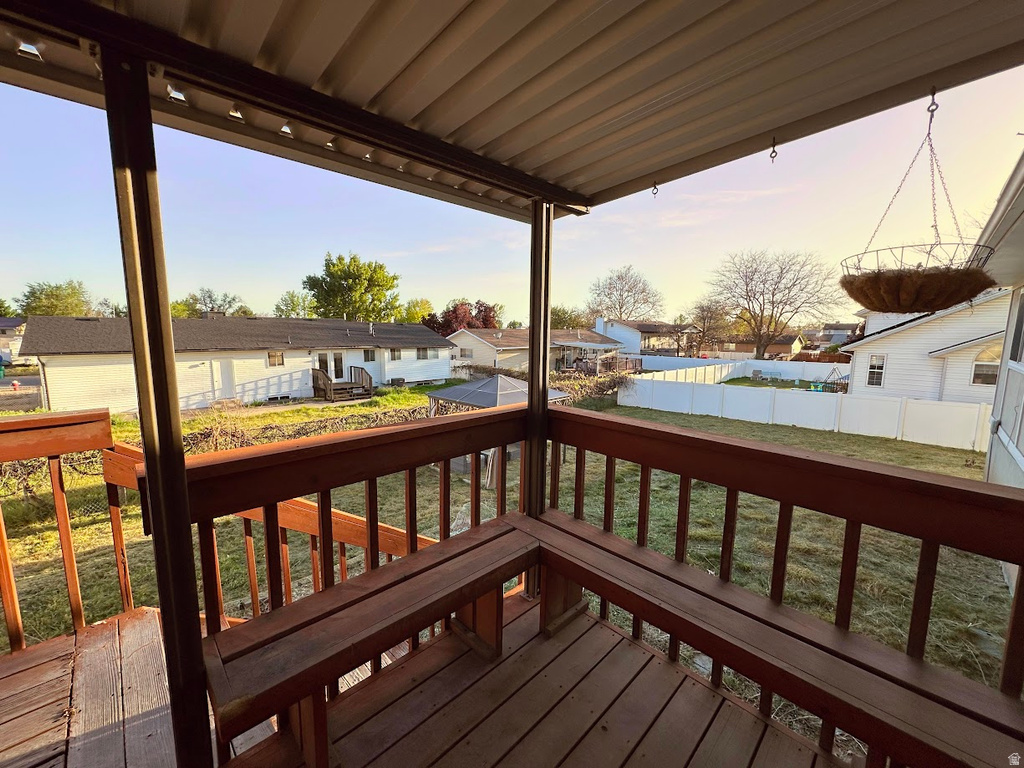 Covered wood deck featuring built-in bench seating, wood railing, and a slatted composite roof