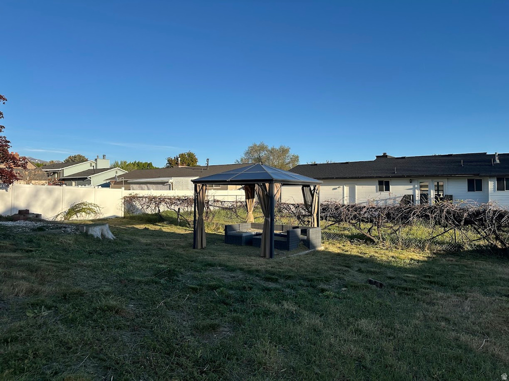 Expansive backyard featuring a covered gazebo, mature plantings, and a solid perimeter fence