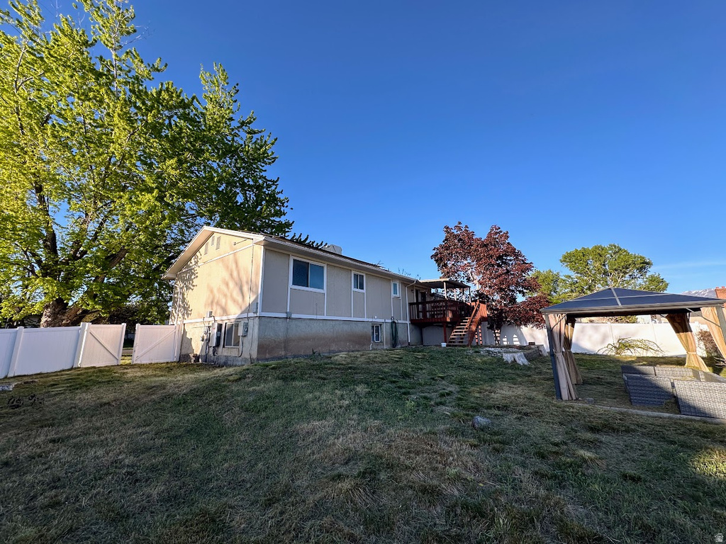 Expansive backyard featuring a multi-level deck with stairs, mature trees, and a white privacy fence
