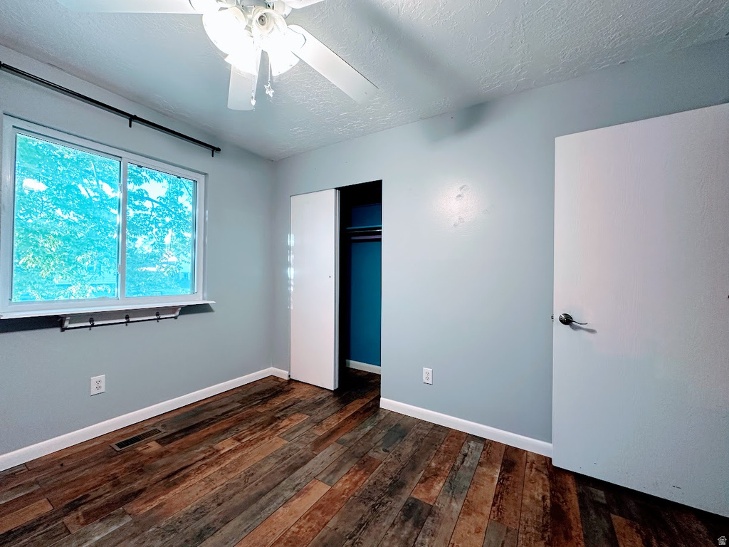 Room featuring wood-finish flooring, a window with a white frame, and a ceiling fan