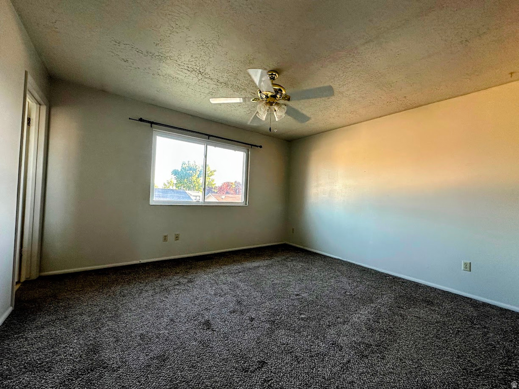 Spacious room featuring neutral wall tones and dark gray carpeting