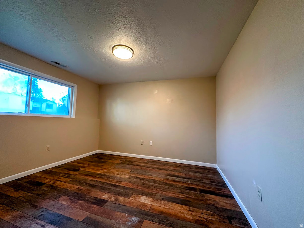 Room featuring wood-finish flooring, a rectangular window with white trim, a flush-mount ceiling light fixture, and light beige wall paint