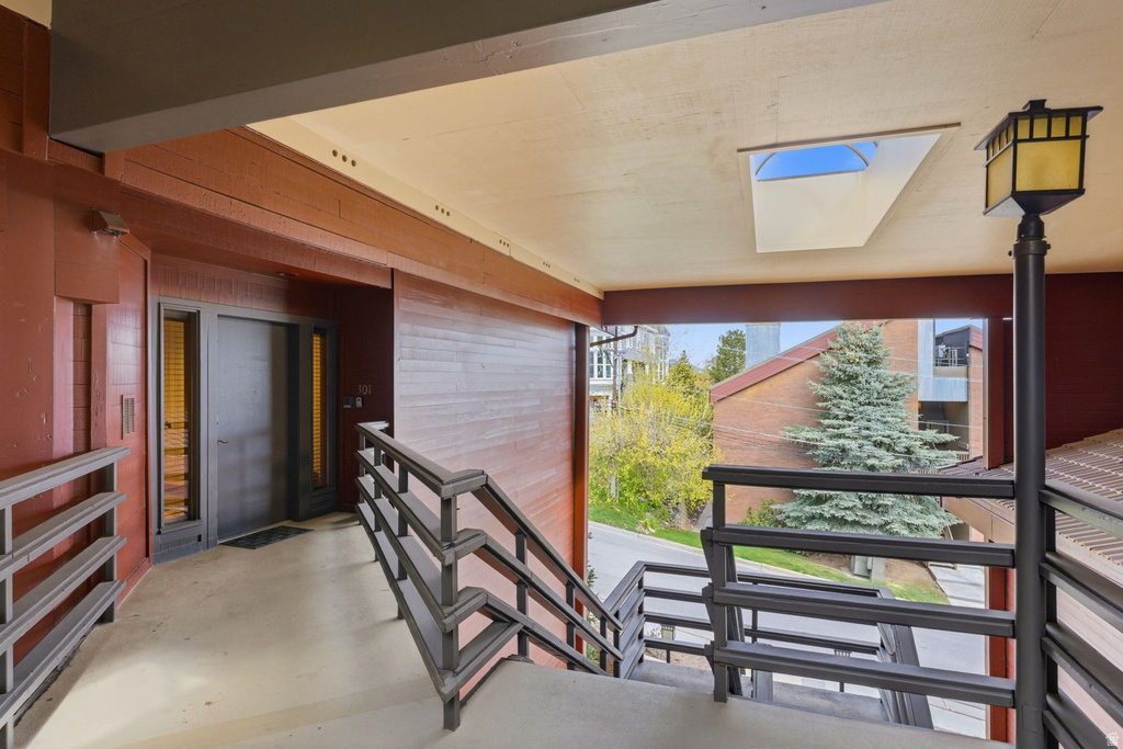 Exterior entrance featuring a dark gray door with vertical sidelight windows, a skylight, and a decorative outdoor post lamp