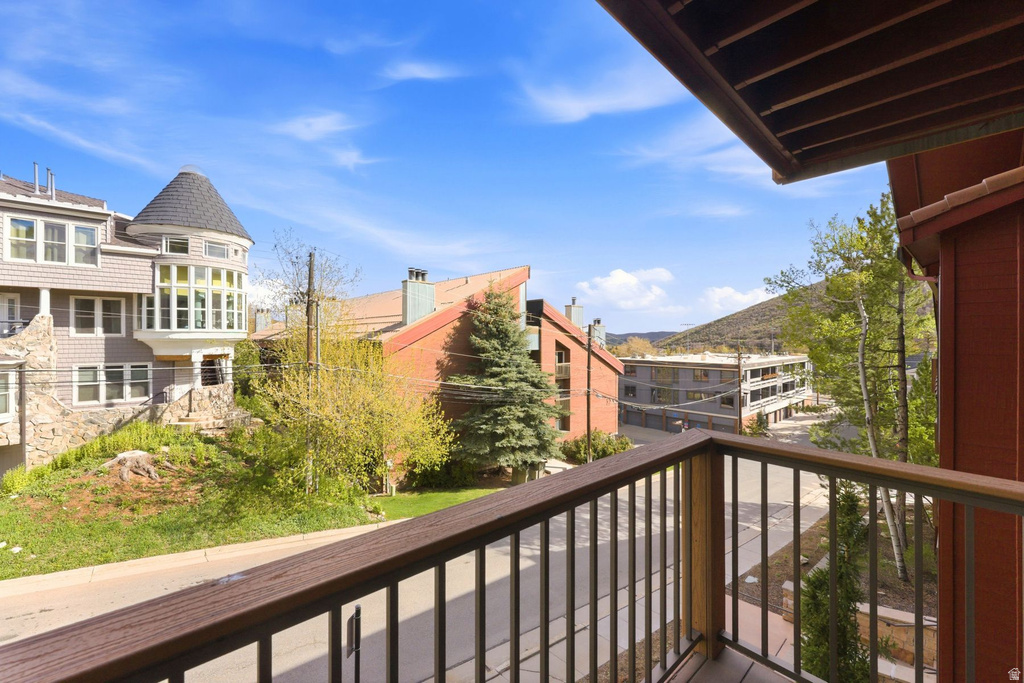 Exterior balcony featuring a wood-finish railing and a street-level perspective
