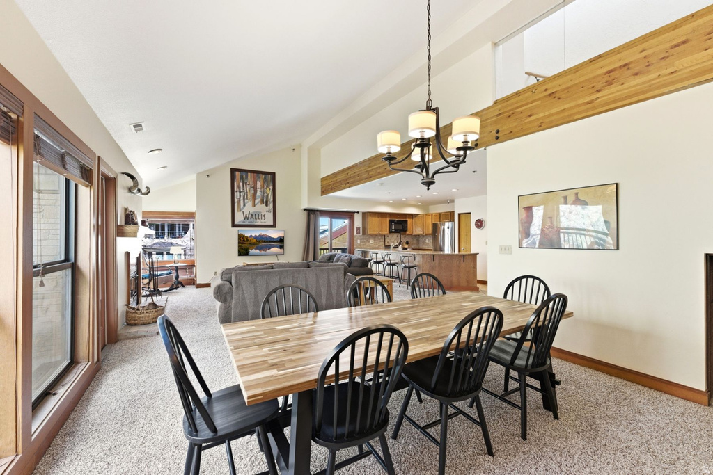 Open-concept dining area featuring vaulted ceilings, a decorative chandelier, and wood-finish flooring