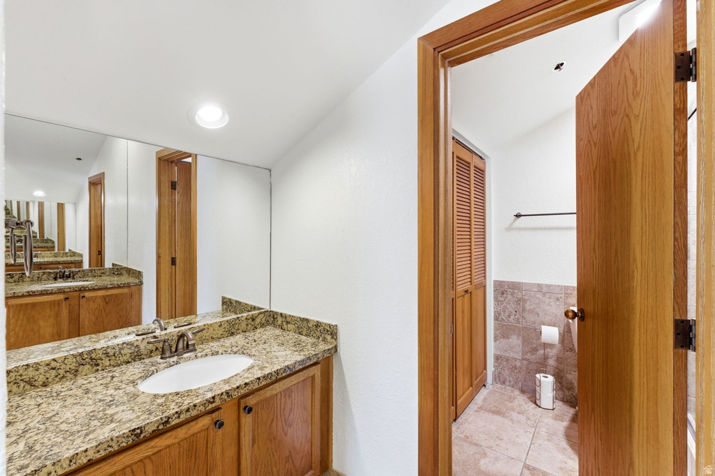 Bathroom vanity featuring a light-colored countertop, an undermount sink, and wood-finish cabinetry