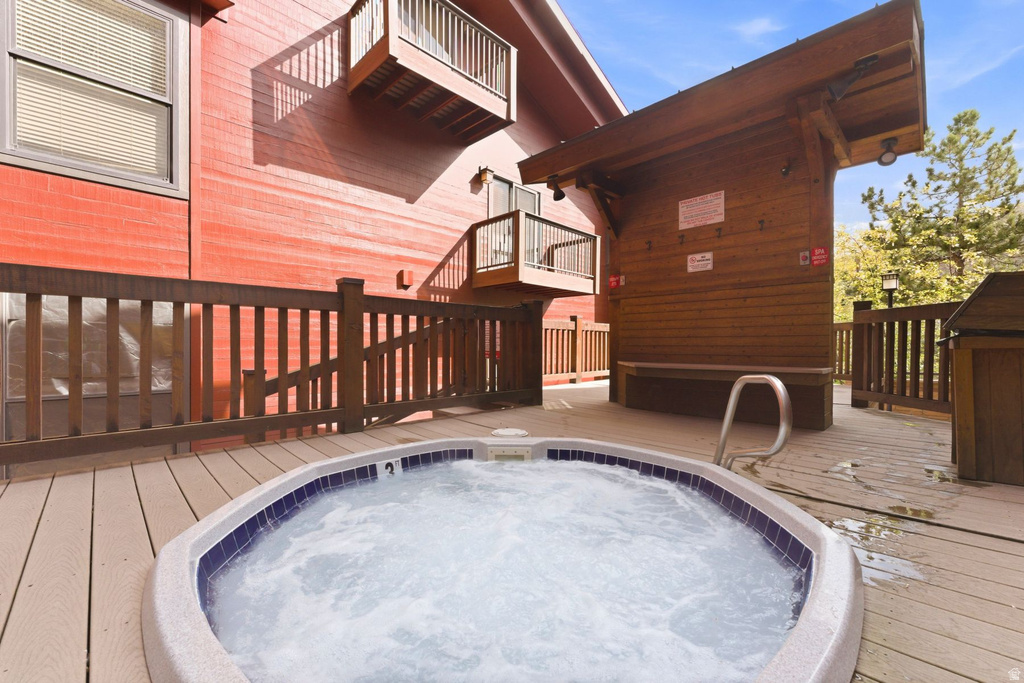 Outdoor hot tub with blue tile surround and stainless steel handrail set on a composite deck