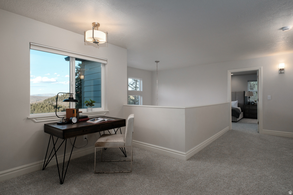 Upper-level landing featuring a window with a mountain backdrop, plush carpeting, a partial wall with a railing, and contemporary wall sconce lighting