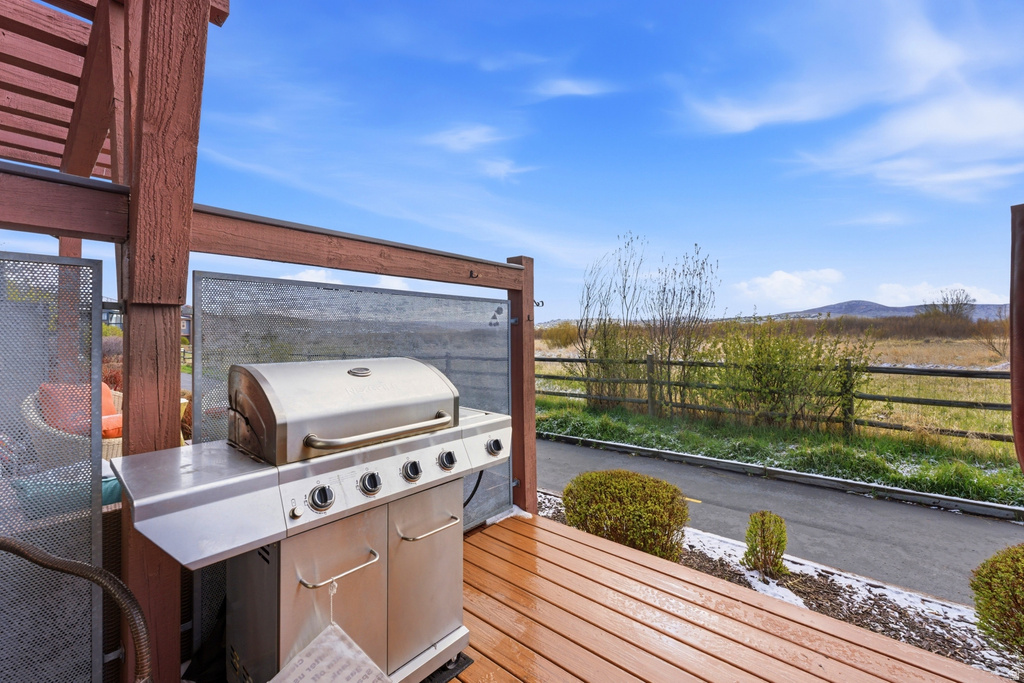 Private outdoor deck featuring wood-finish flooring, an overhead pergola structure, and a partial privacy screen