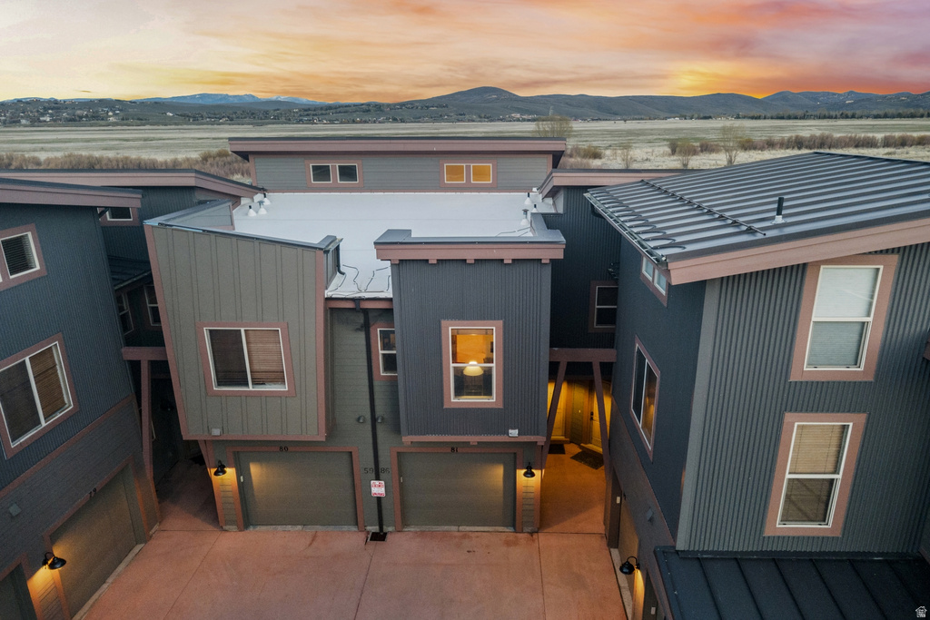 Modern multi-story townhome featuring corrugated metal siding, distinct rooflines, and individual garages