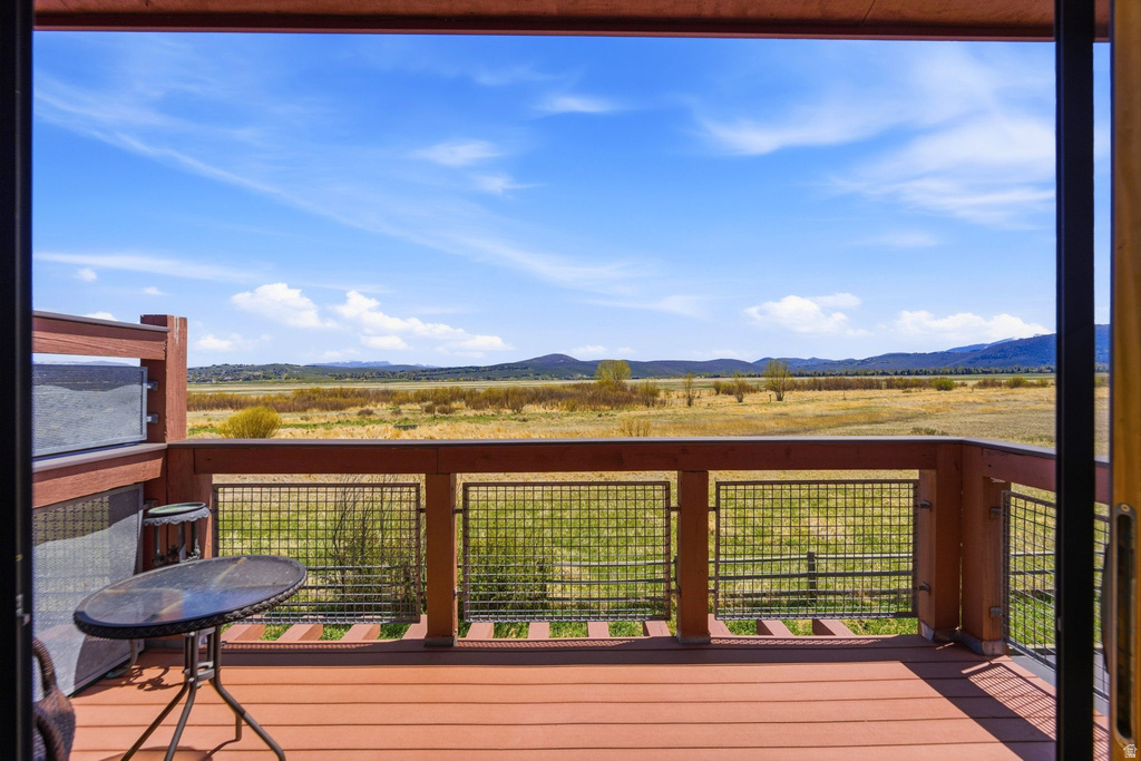 Spacious deck featuring wood-finish flooring and a wood railing with metal grid inserts, overlooking expansive open terrain