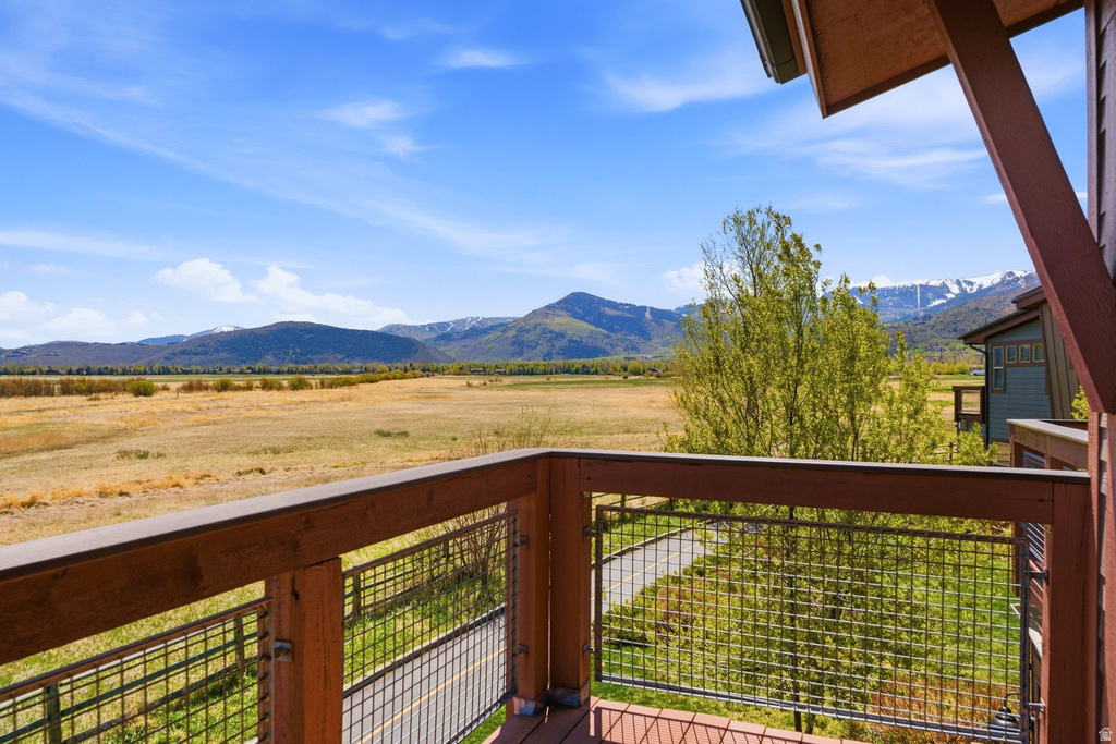 Expansive mountain scenery with a foreground of natural grassland visible from a private balcony