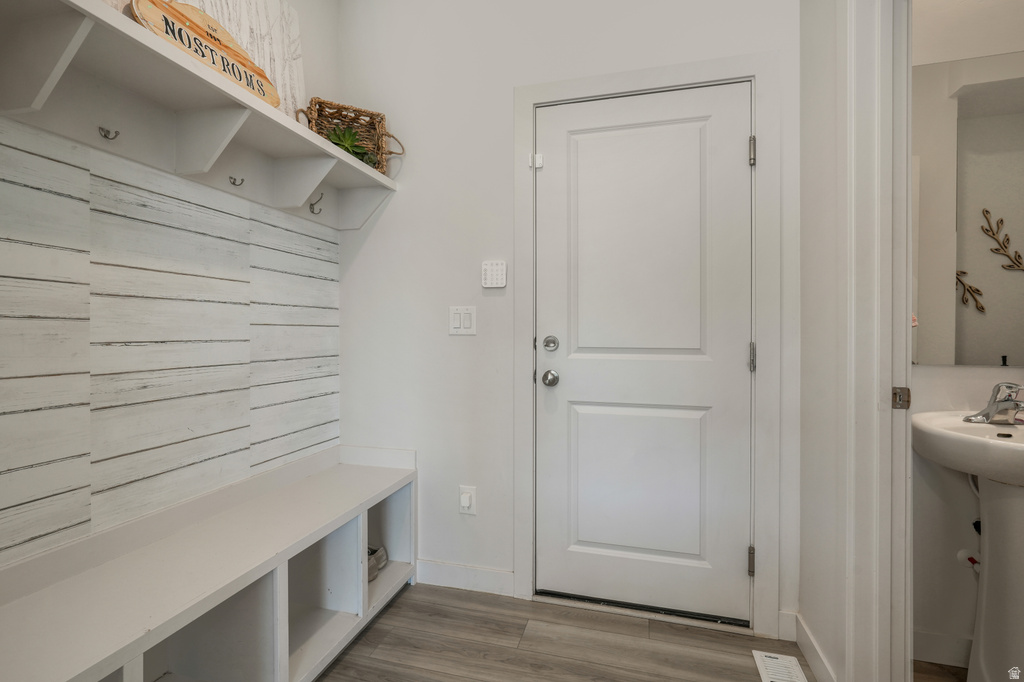 Entryway featuring a built-in bench with storage, shiplap-style wall paneling, and an integrated shelf with coat hooks