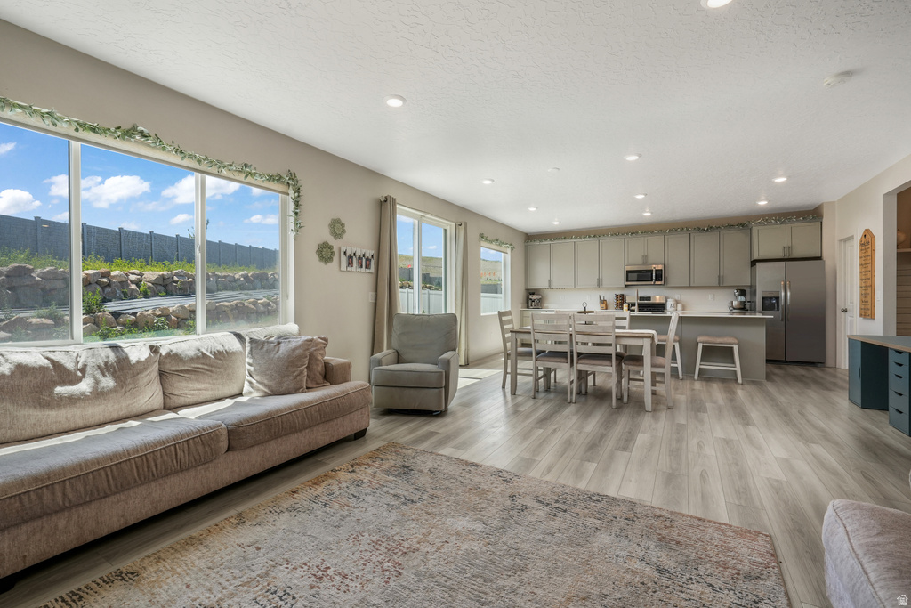 Open-concept living area featuring wood-finish flooring, recessed lighting, and large windows
