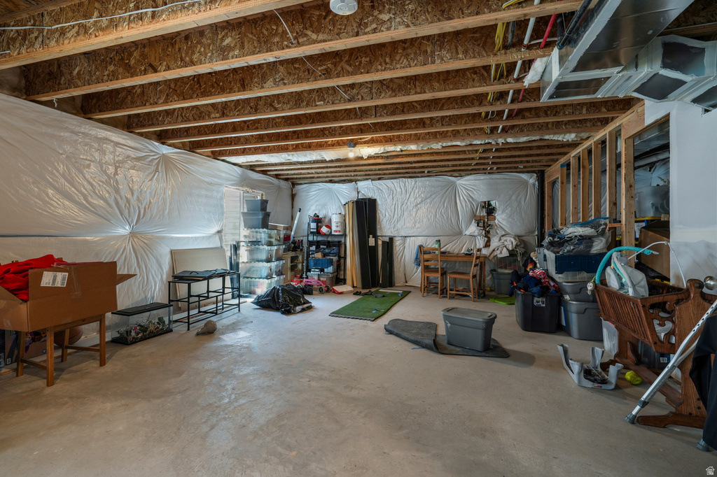 Unfinished basement featuring exposed wood joists, concrete flooring, and insulated walls
