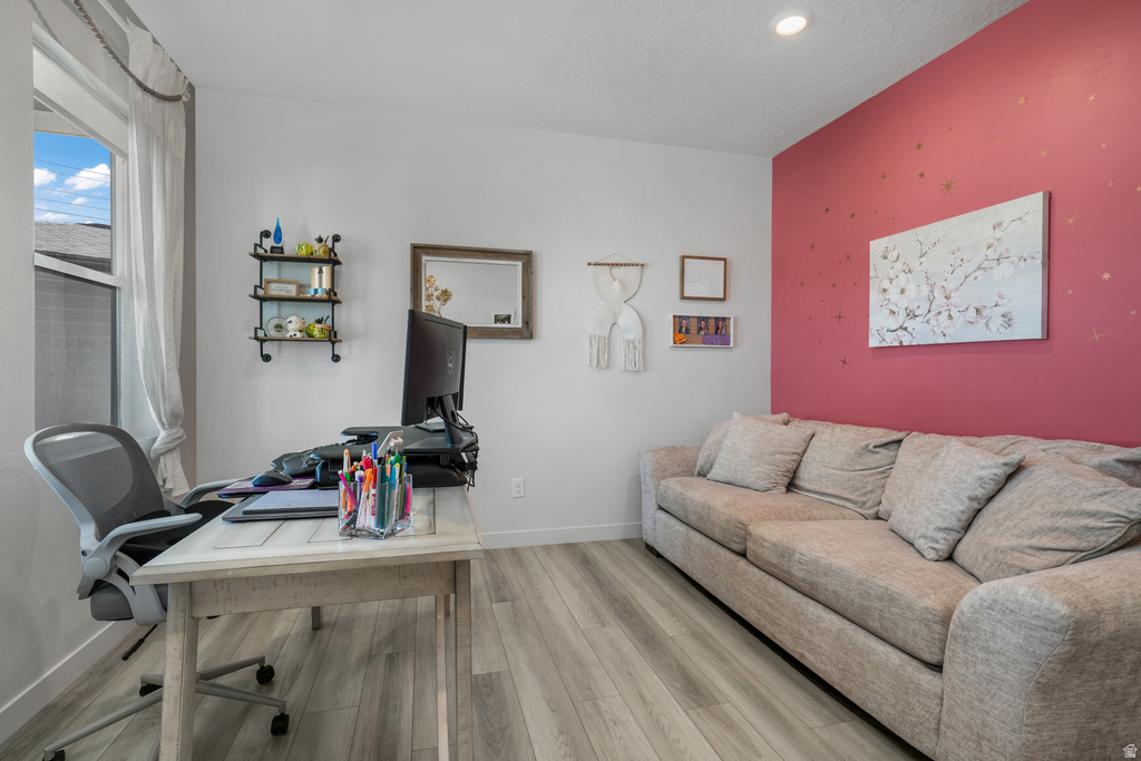 Spacious room featuring light wood-finish flooring, recessed lighting, and a large window with white trim