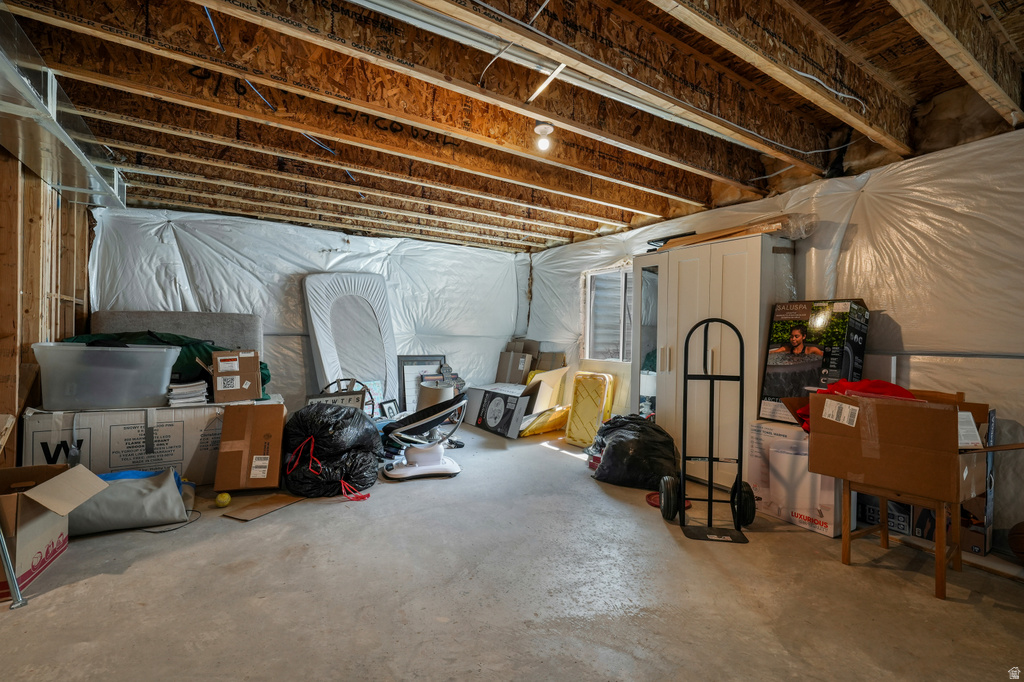 Unfinished basement with concrete flooring and visible wooden joists and beams