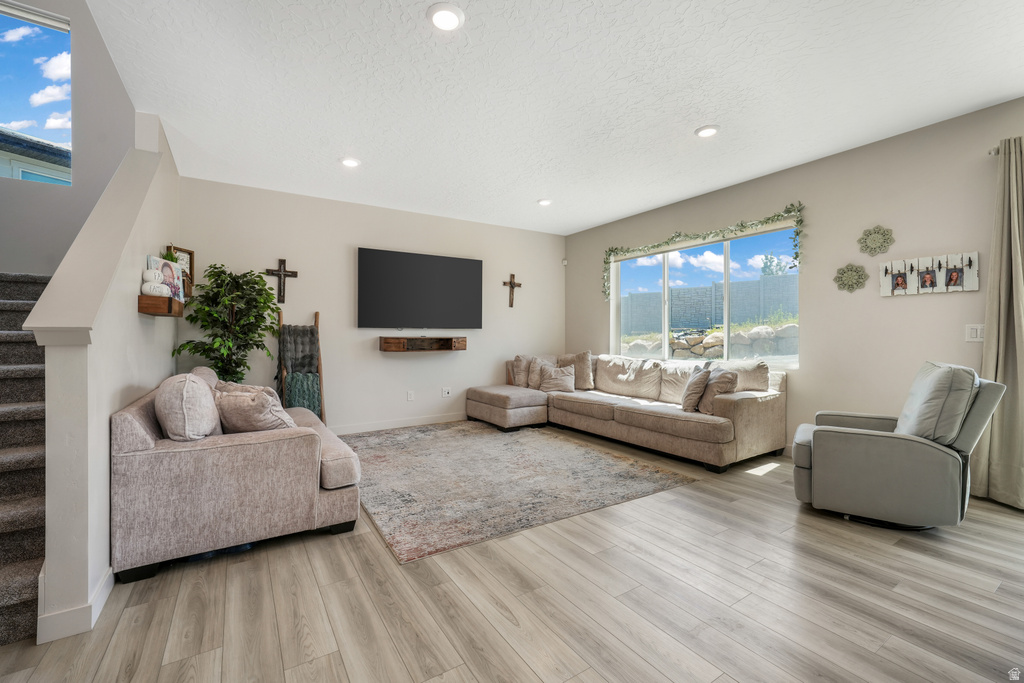 Spacious living area featuring light wood-finish flooring, recessed lighting, and a large picture window