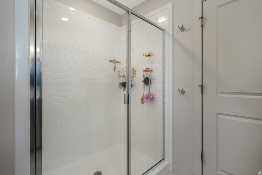 Shower enclosure featuring a clear glass door, white subway tile surround, and recessed lighting
