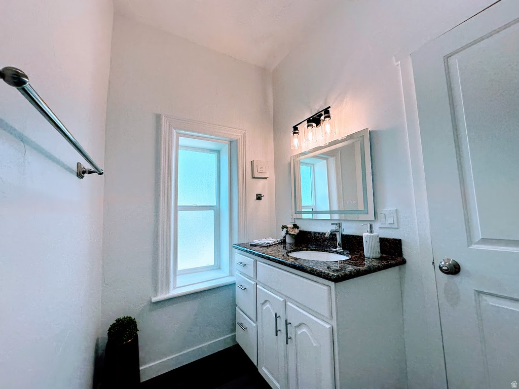 Bathroom featuring a white vanity with panel cabinetry and silver hardware, a speckled granite countertop, and an undermount sink with a chrome faucet