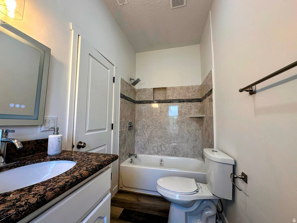 Bathroom featuring a white vanity with a dark speckled countertop, an undermount sink, and a framed mirror with integrated lighting