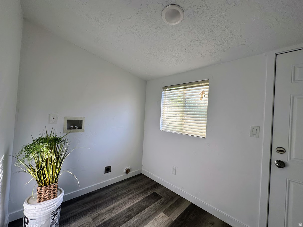 Laundry area featuring wood-finish flooring, white walls, and a window with blinds