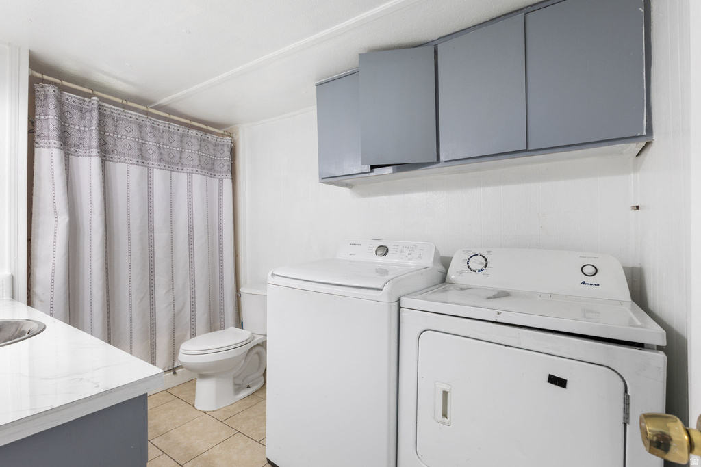Laundry area featuring white appliances, upper storage cabinetry, and tiled flooring