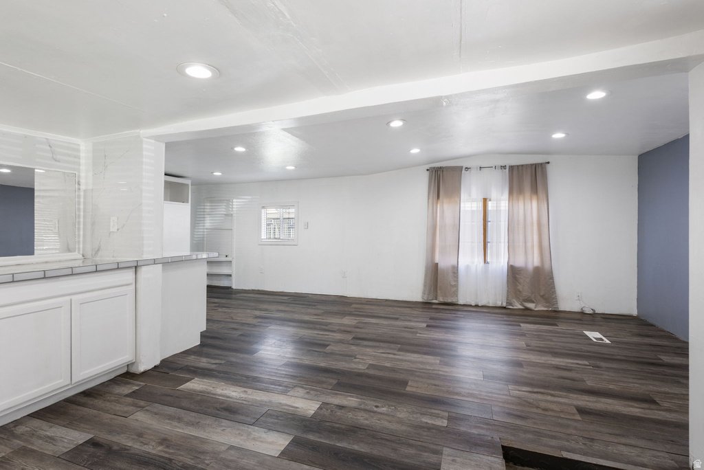 Open-concept living space featuring wood-finish flooring, recessed lighting, white cabinetry, and a countertop with a tile backsplash