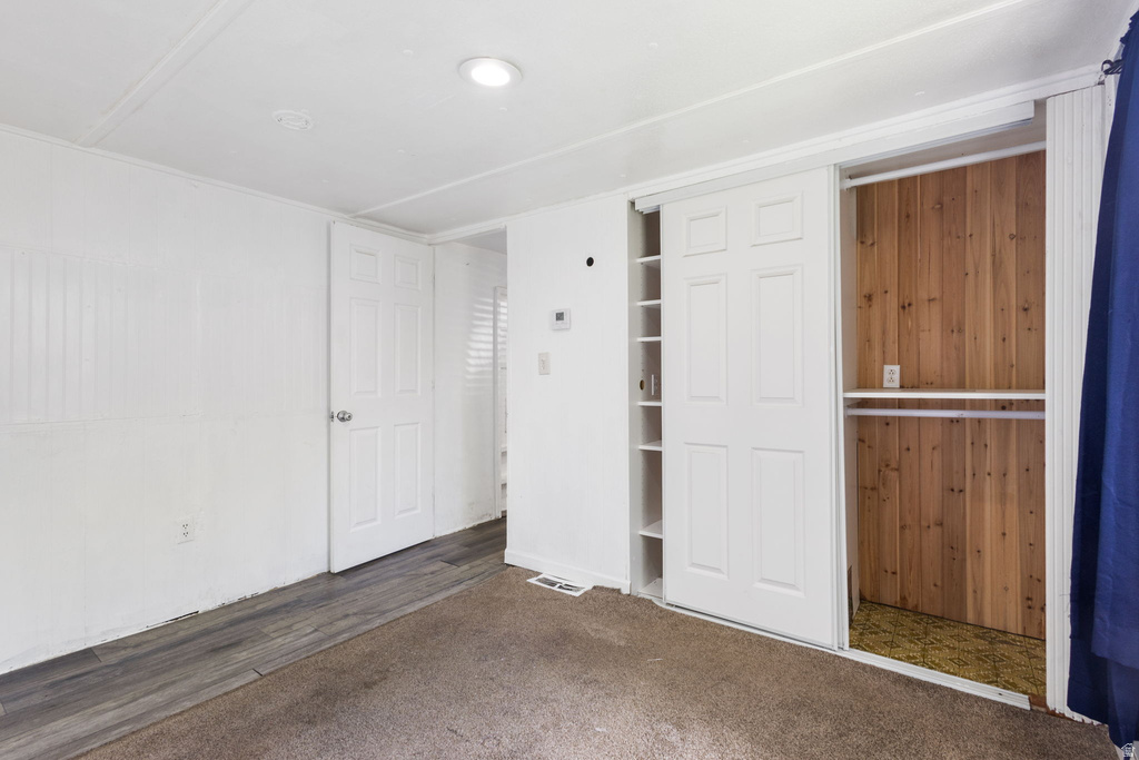 Carpeted room featuring a white paneled wall, recessed ceiling lighting, and a white six-panel door