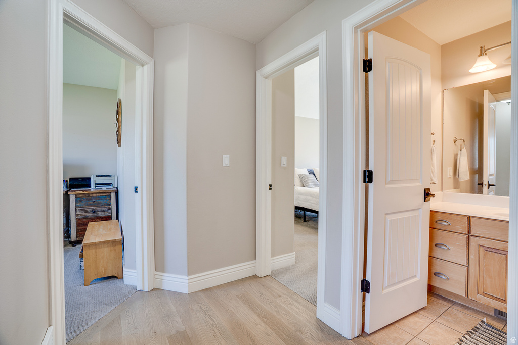 Hallway featuring wood-finish flooring, light neutral paint, and white trim